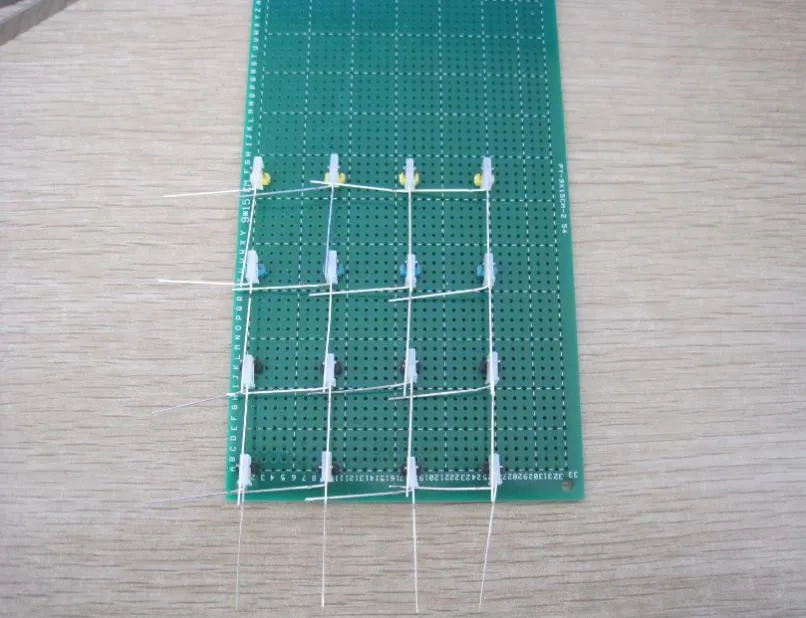 同一块绿色万用板，16 颗整形好的 LED 已夹在排针之间排成四行四列，引脚横竖相连成网格
