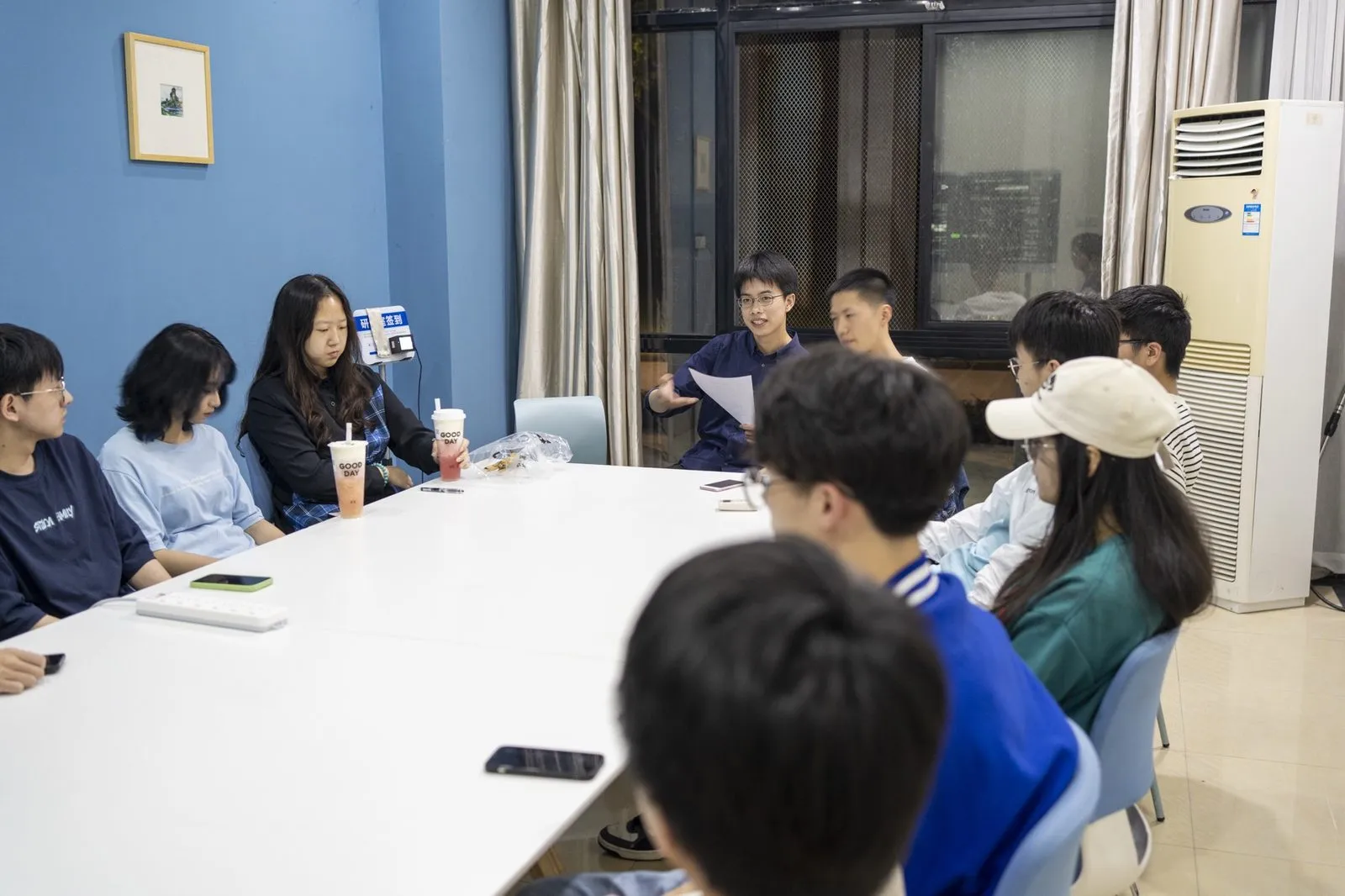 例会现场，成员围着长桌讨论社内事务