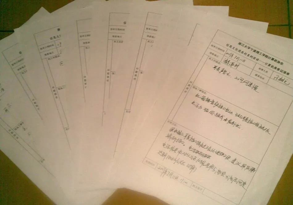 桌上摊开一叠手写的表格，抬头印着“浙江大学宁波理工学院计算机协会　信息文化进农村系列活动——计算机服务记录单”；最上面一张已填写，可见“服务日期时间”“服务地点”“服务人员”“问题描述”等栏目，字迹已难辨认