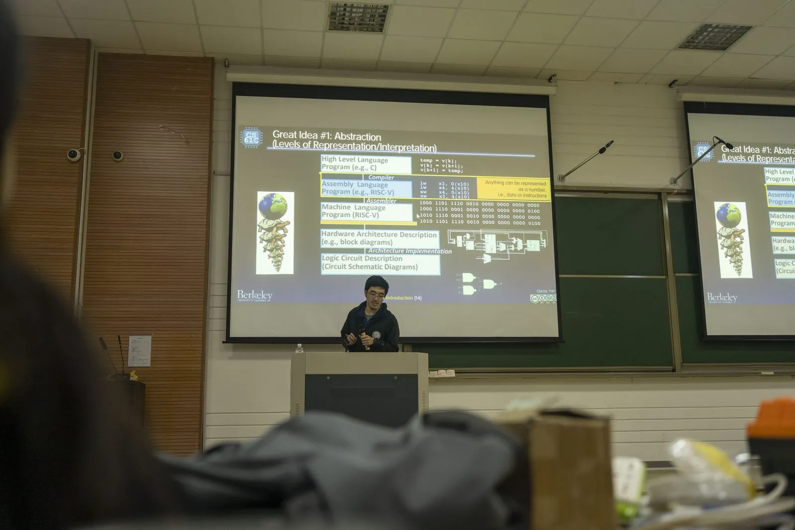 分享会现场，投影上是伯克利 CS61C 课程的幻灯片“Great Idea #1: Abstraction”，列出从高级语言到逻辑电路的表示层次